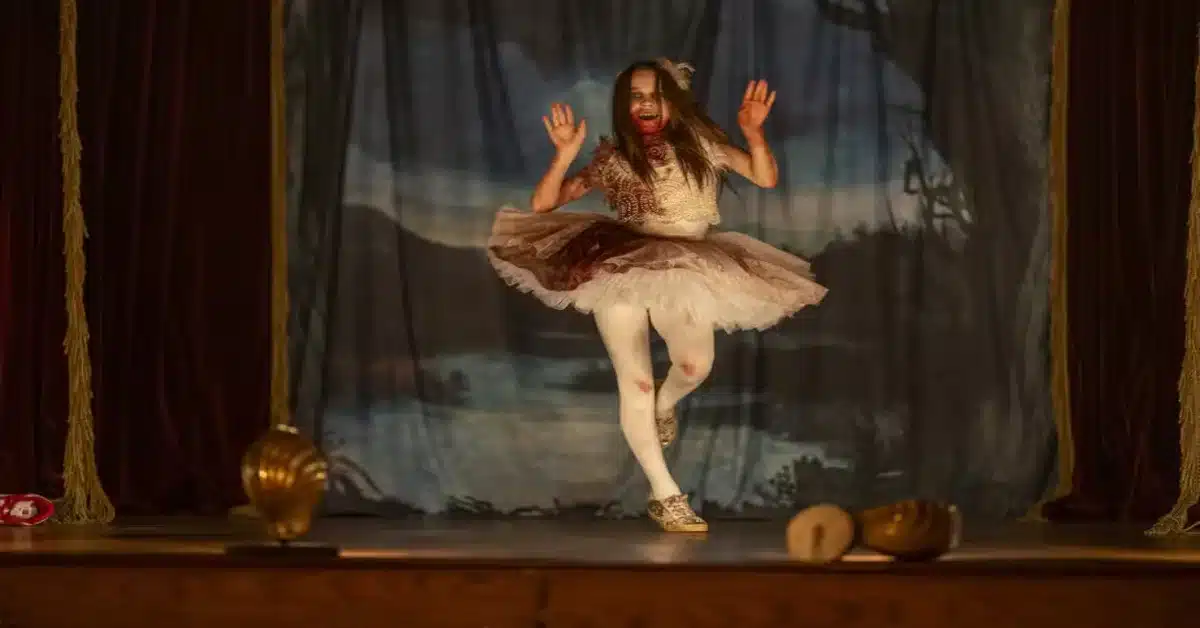 Descrição da imagem: bailarina com dentes de vampiro e sangue dança em um palco. Imagem: Divulgação.